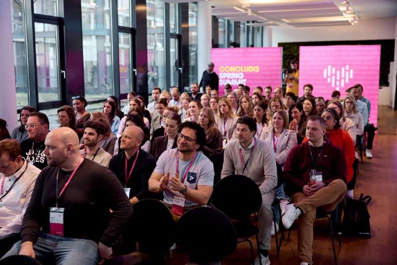 Aufmerksames Publikum beim concludis Spring Summit 2026 vor der pink leuchtenden Eventwall